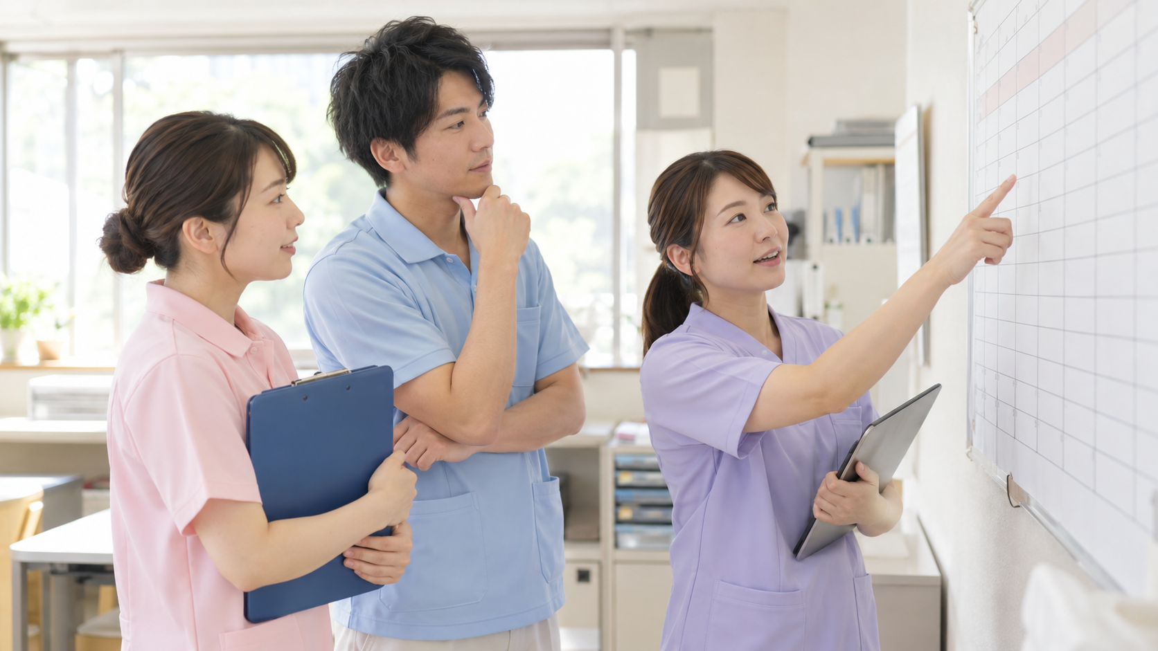 介護施設のスタッフルームでシフト表を見ながら話す介護職員