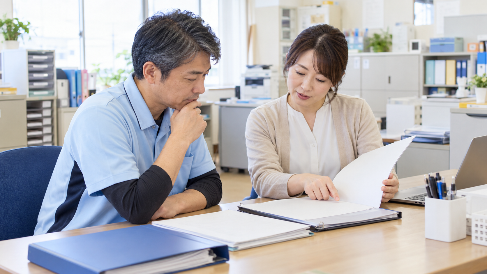 事務室で退職金規程の書類を確認する50代の介護職員